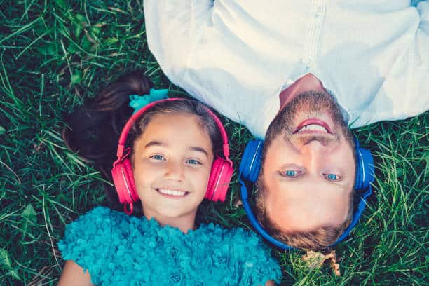 Little girl and father with headphones lying in the grass SSP Sound Therapy