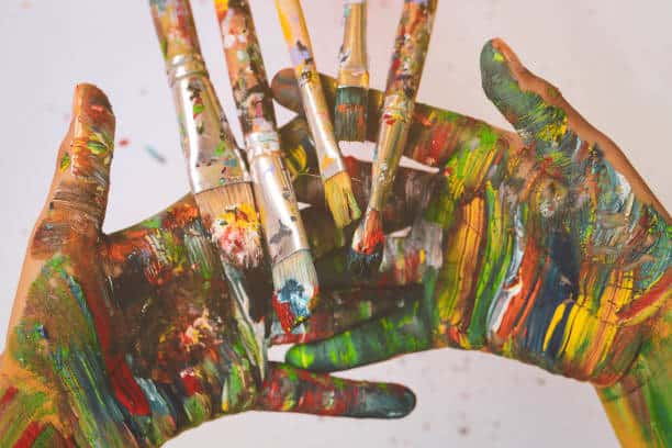 Paintbrushes are on colourful hands painted